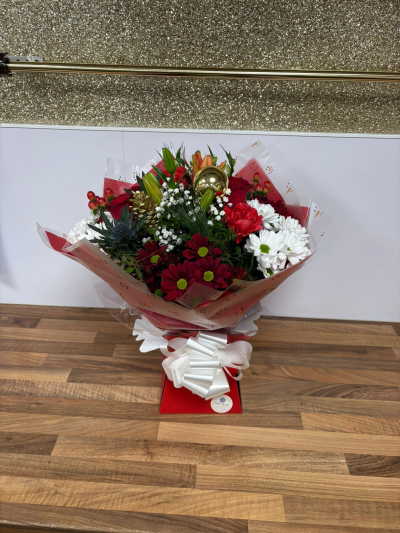 Winter Wonderland Hand-Tied Bouquet - A festive Christmas hand-tied bouquet featuring red roses, chrysanthemums, carnations, berries, winter greenery and gold accents. Beautifully wrapped and delivered in water.