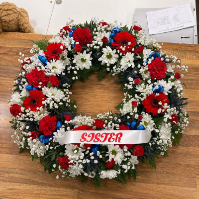 Red & White Wreath - Traditional red and white remembrance wreath with blue ribbon accents and personalised tribute ribbon for a beloved sister.