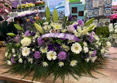 Lavender Coffin Spray - Graceful lavender casket spray with lilies and delicate seasonal flowers for an elegant farewell tribute.