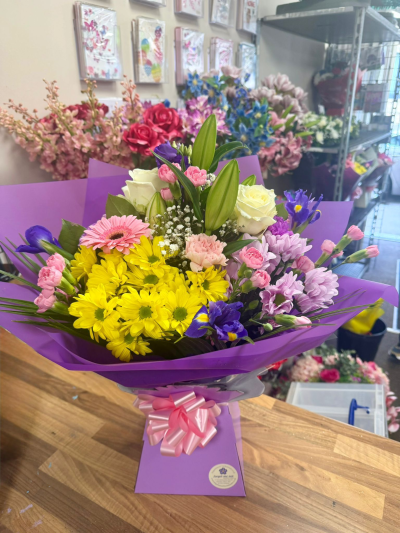 Sweet Meadow Hand-Tied - Bright and cheerful hand-tied bouquet with yellow gerberas, cerise carnations and seasonal blooms in vibrant pink wrapping.